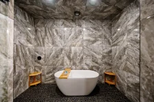 Modern luxury bathroom featuring a freestanding tub surrounded by elegant marble walls and stylish wooden