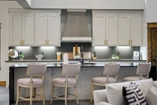Modern kitchen with waterfall countertops, stainless steel range hood, and bar seating in II Elks