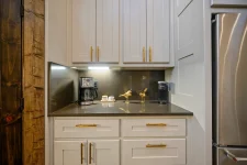 Modern gourmet kitchen area with white cabinetry, gold hardware, and countertop appliances in II Elks